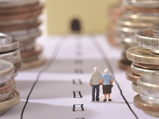 figurine of old people amongst coin stacks