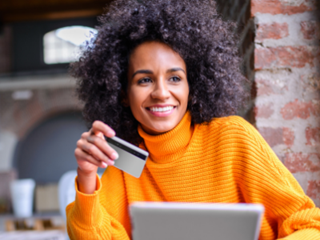 a woman holding an electronic tablet in one hand and a bank card in the other
