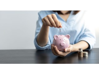 Woman placing coin in piggy bank
