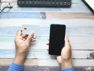 a person holding a bank card and a phone
