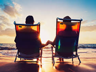 couple sitting in deck chairs at the beach at sunset