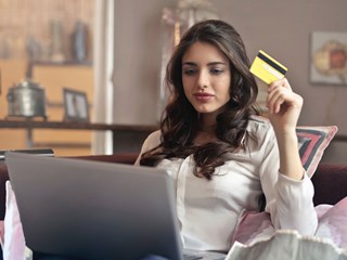woman looking at laptop holding bank card