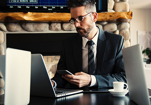 man looking at laptop and holding phone