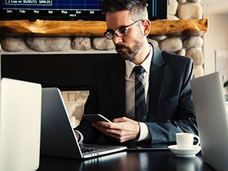 man looking at laptop and holding phone