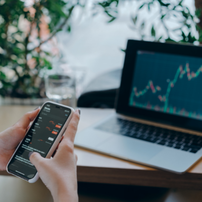 a person checking their phone looking at a stocks and shares graph