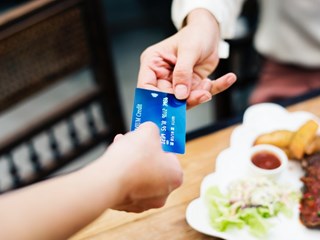 woman handing over card to pay in restaurant