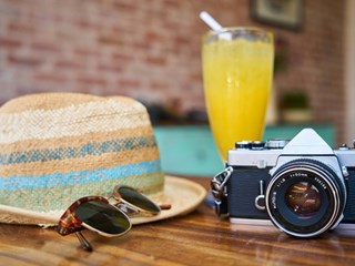 camera hat and sunglasses on wooden table