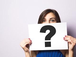 woman holding up paper question mark