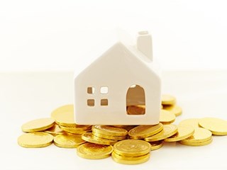 model house on top of pile of coins