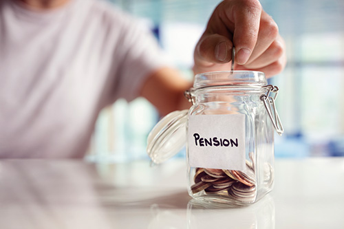 Person depositing a coin in a jar labelled 'pensions'