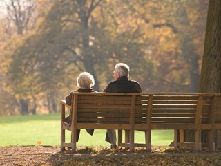 elderly couple sat on a bench in the park