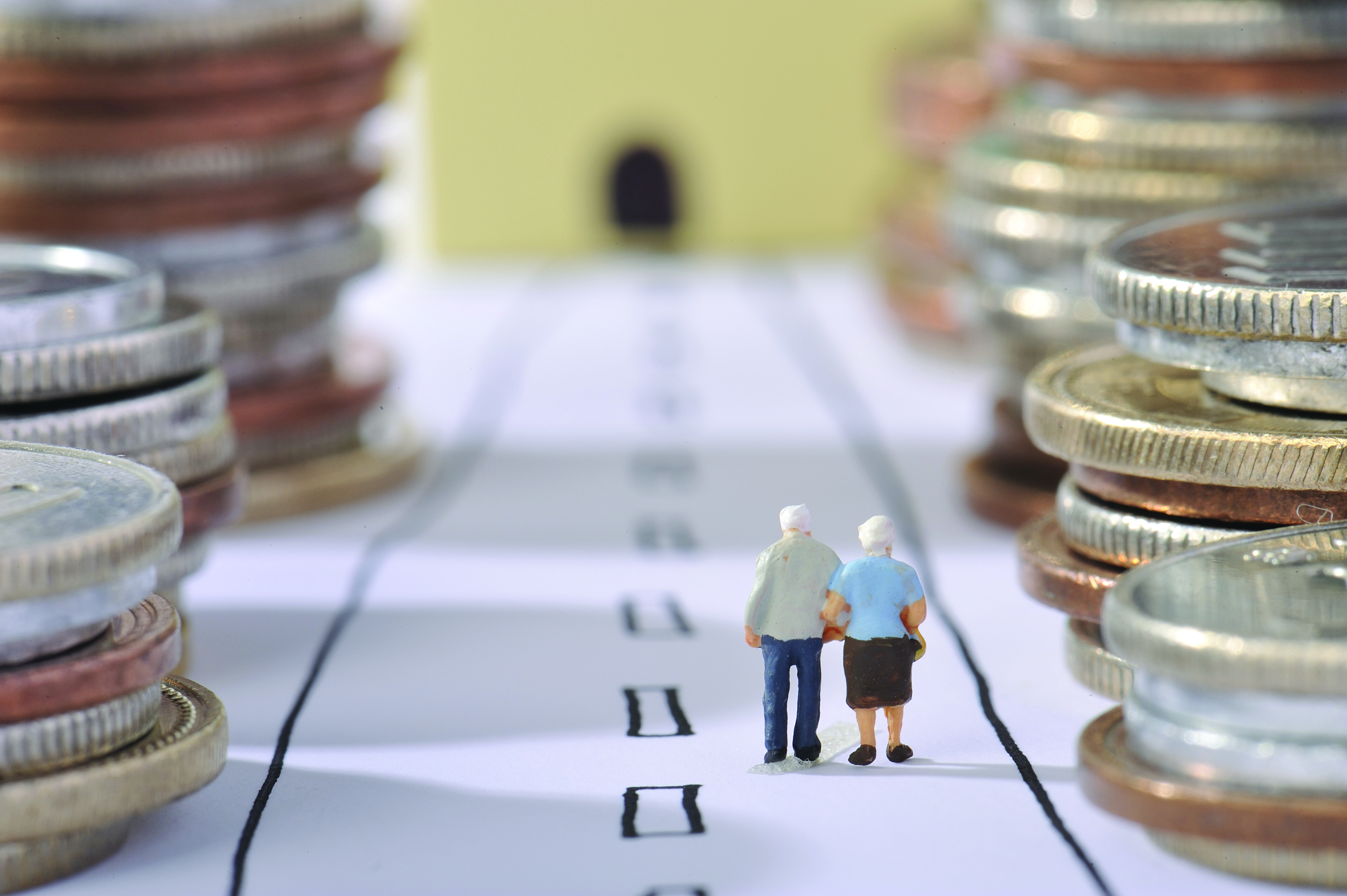 figurine of old people amongst coin stacks