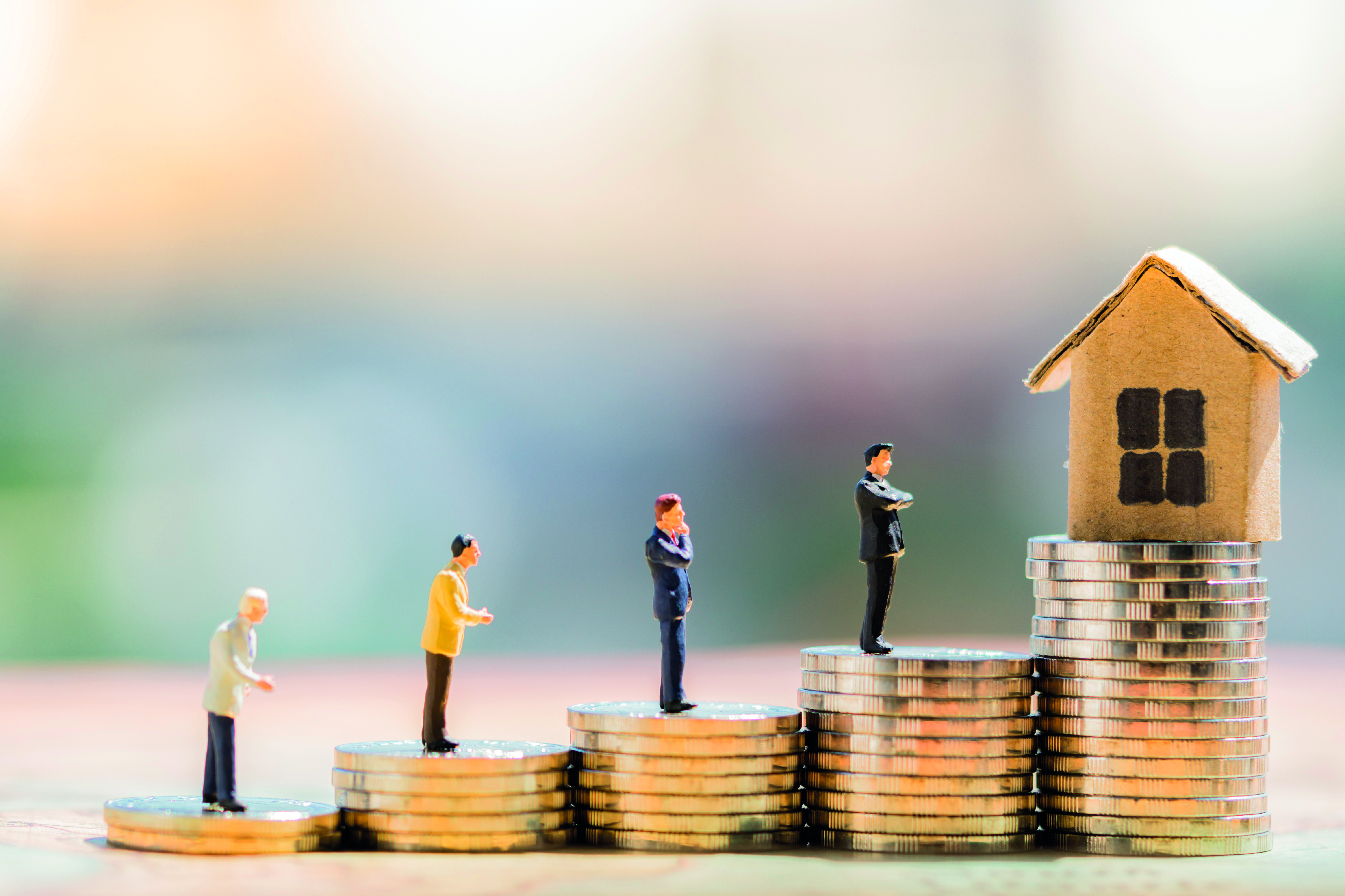 a stack of coins leading to a model home a mortgage metaphor