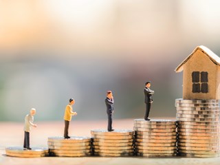 a stack of coins leading to a model home a mortgage metaphor