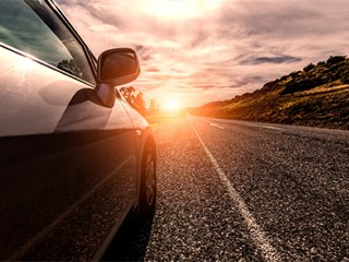 car driving towards the sunset