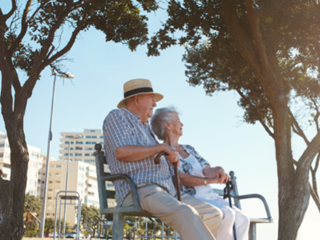 Older couple sitting together on a bench looking into the distance