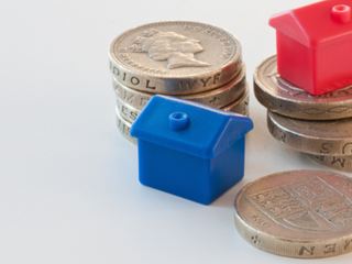 plastic monopoly houses sitting on top of pound coins