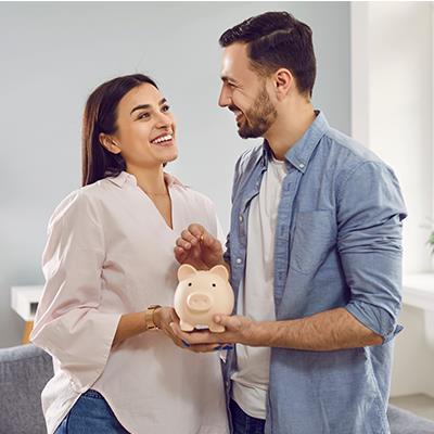 Man and woman, standing, holding a piggy bank.