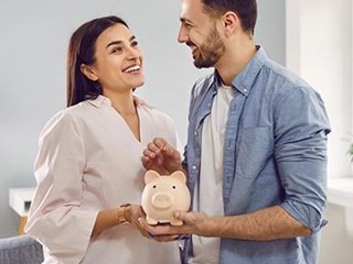 Man and woman, standing, holding a piggy bank.