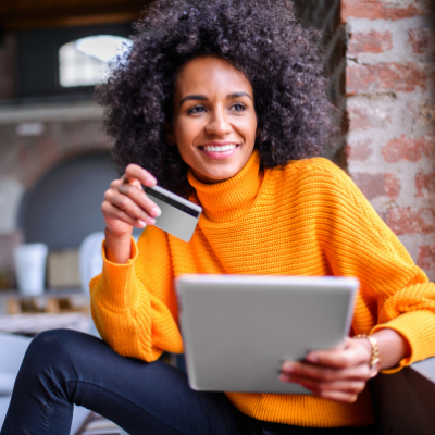 a woman holding an electronic tablet in one hand and a bank card in the other