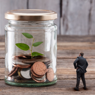 figurine of man standing beside a large jar of coins