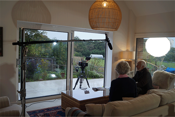 Image of a couple sat on a sofa underneath a boom microphone.