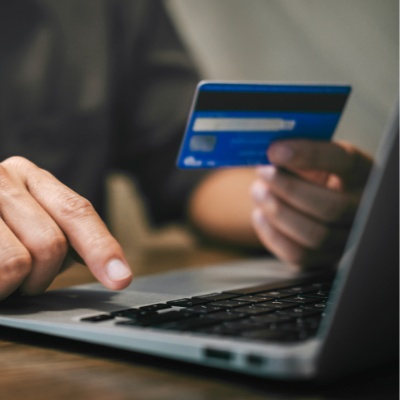 man typing his bank card details into a laptop