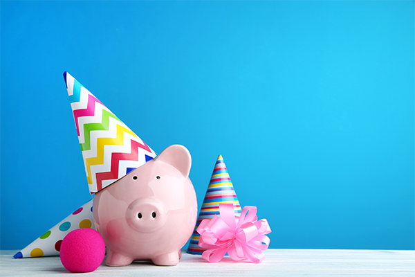 Piggy bank wearing party hat with streamers.