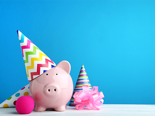 Piggy bank wearing party hat with streamers.