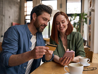 Couple sat at a table comparing products using a mobile phone