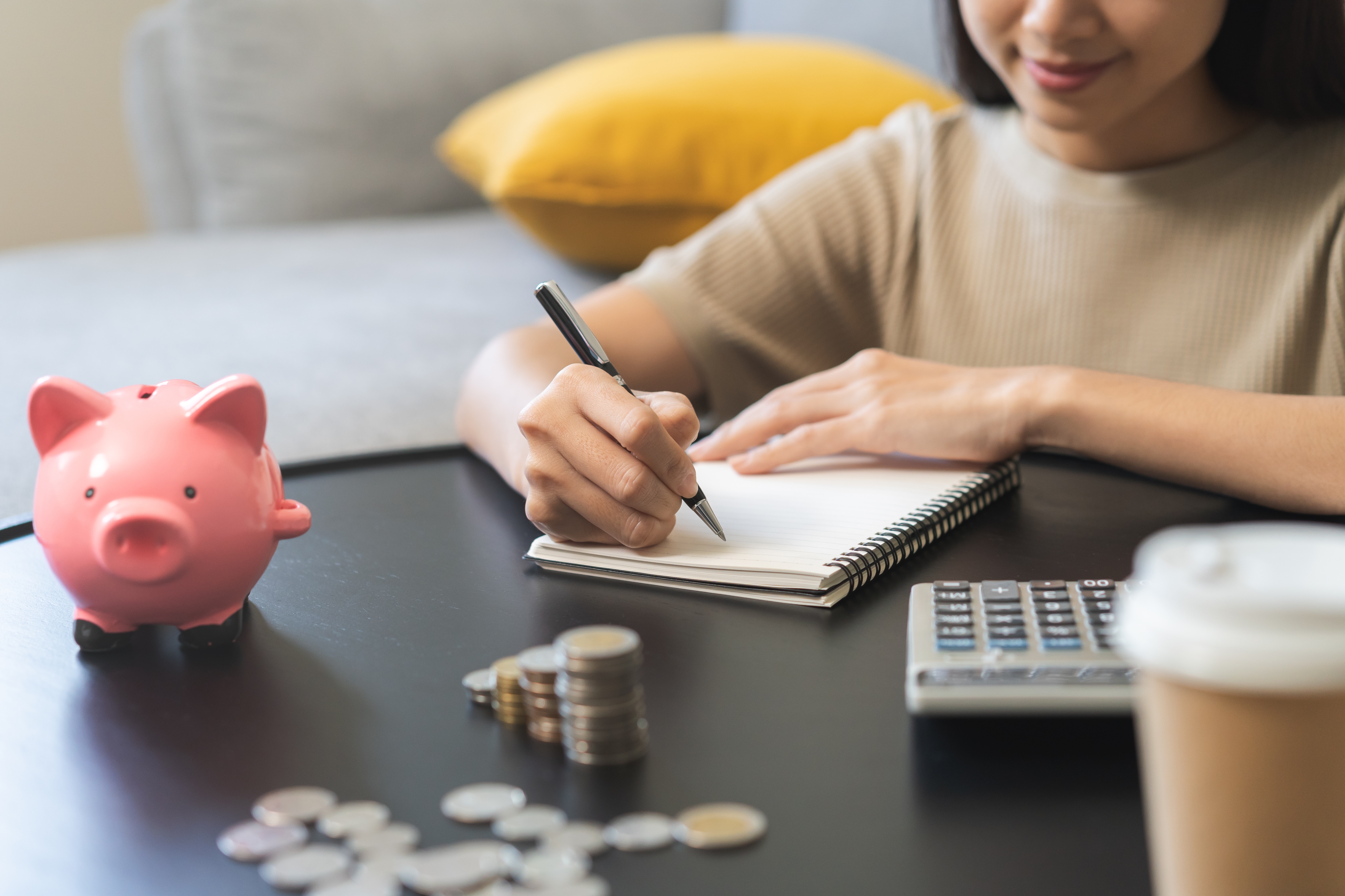 Woman counting savings, coin stacks, calculator and piggy bank