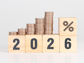 Wooden blocks spelling '2026' with coins stacked on top.