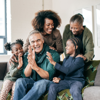 family with grandparents laughing on a sofa