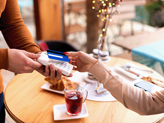 Woman in a cafe making a contactless card payment