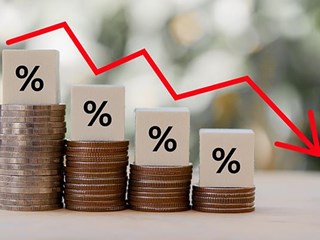 Percentage signs sitting on stacks of coins, progressively getting shorter with downward arrow.