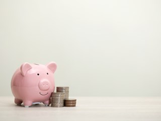 Piggy bank next to coin stacks