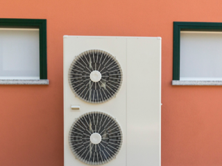 Air source heat pump against an orange wall