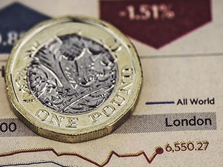 Pound coin on top of graph tracking stocks performance.