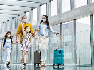 a family walking through an airport with masks on their faces