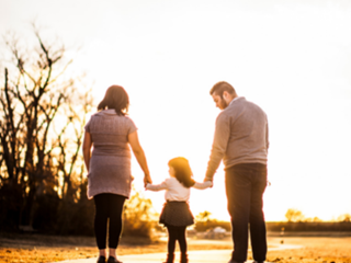 a family of three walking into the sunset