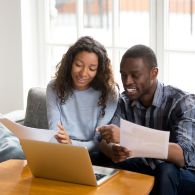 couple looking at finances on paper and the laptop