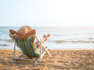 person laying on a sun-lounger on the beach