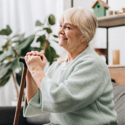 woman sat in chair holding a walking stick