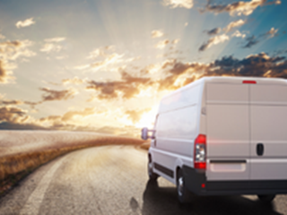 White van driving into a sunset