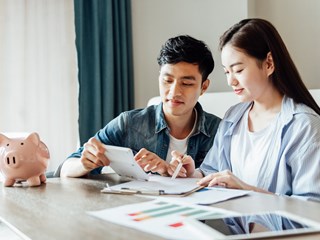 young couple sitting at a table discussing paperwork