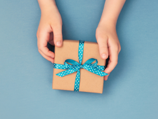 Hands holding a present box wrapped in blue ribbon