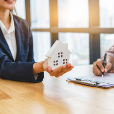 persons hand holding a white house in her palm