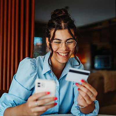 Woman holding a phone and bank card looking happy