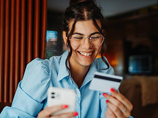 Woman holding a phone and bank card looking happy