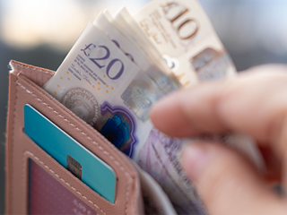 A hand pulling bank notes from a wallet.